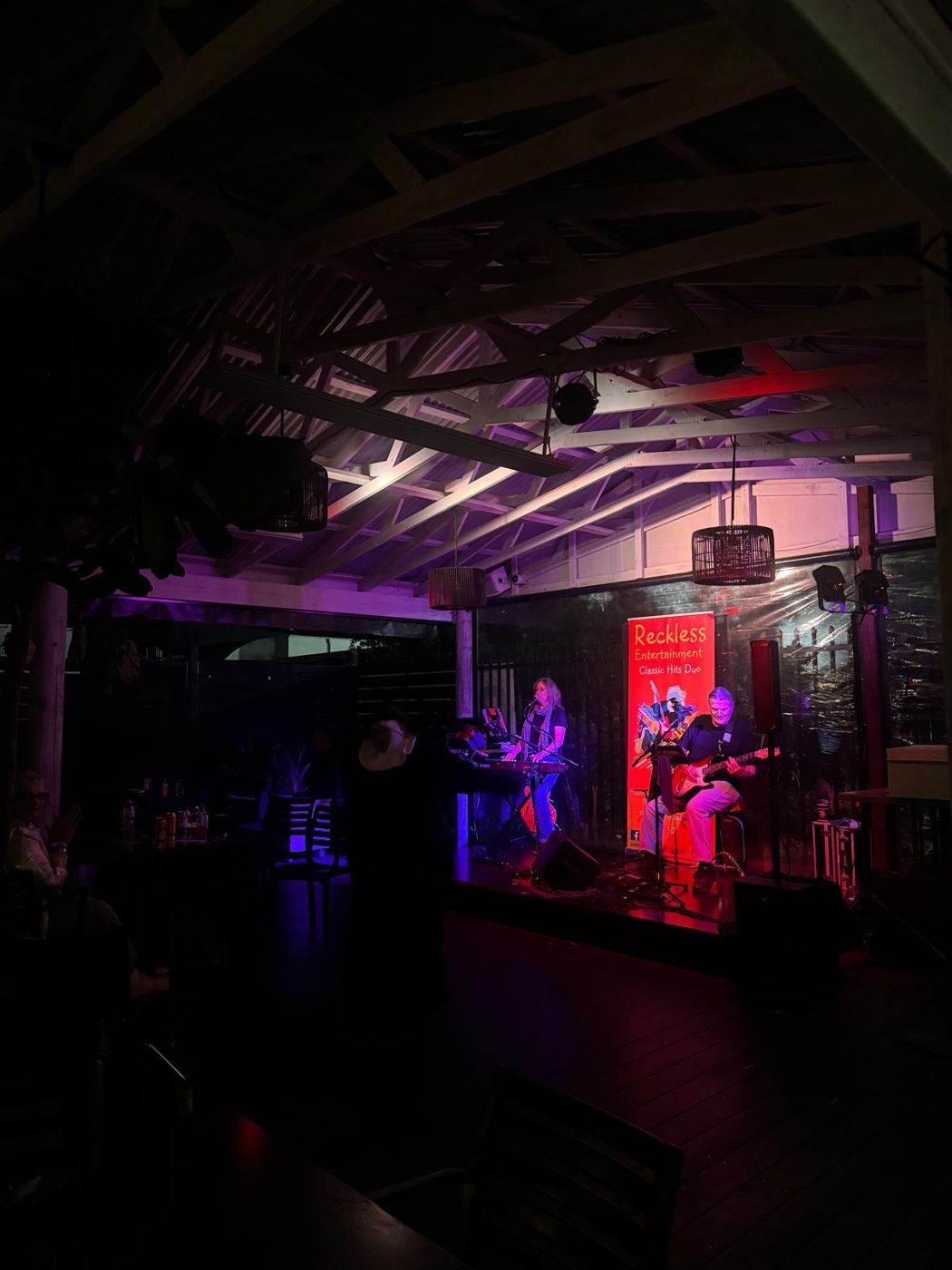 A live duo performing on the Terrace stage at night under colourful lights
